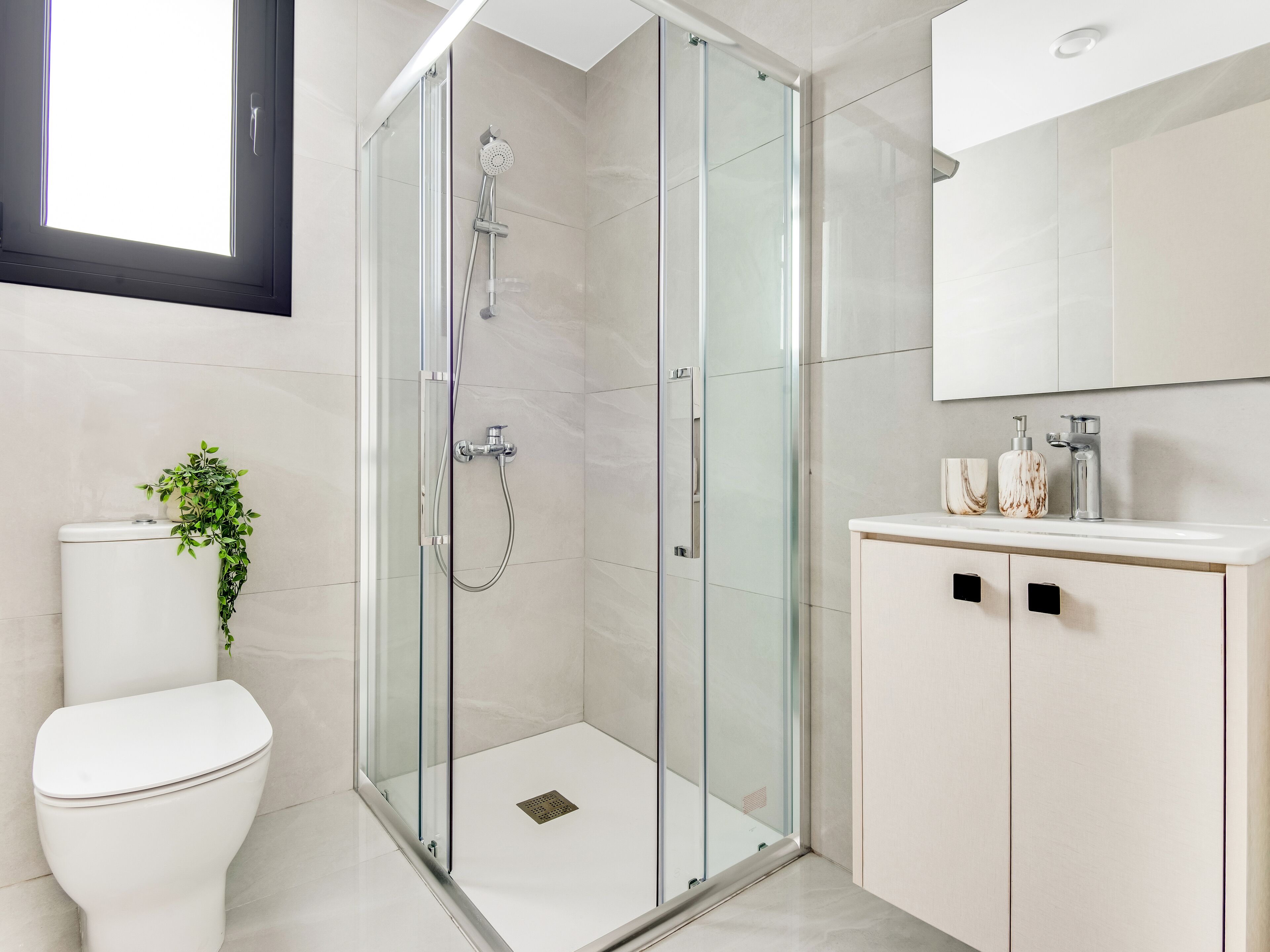 Une salle de bain moderne avec une douche à parois de verre, des toilettes et un meuble-lavabo avec un miroir.