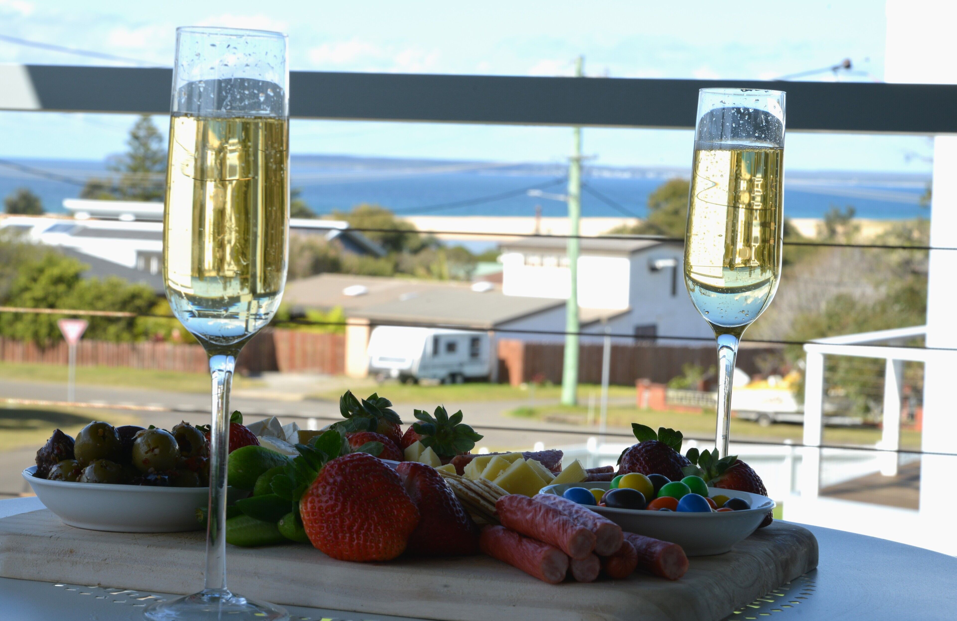Two glasses of champagne on a table with a variety of fruits and vegetables.