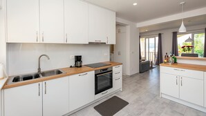 A modern kitchen with white cabinets, a wooden countertop, a built-in oven, and a coffee maker. - Apartments Peaceful Place (Stanici)