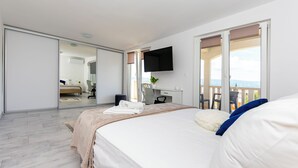 A bedroom with a bed, a desk, a chair, a TV, and a balcony with a view. - Apartments Peaceful Place (Stanici)