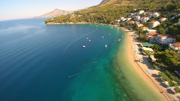 A coastal town with a clear blue sea, boats, and houses along the shoreline. - Apartments Peaceful Place (Stanici)