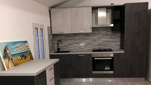 Una cocina moderna con armarios grises, salpicadero de azulejos y una estufa. En la mesa, una escultura de pez turquesa.