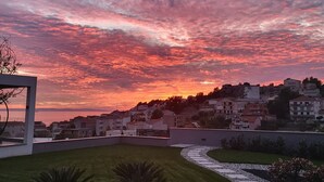 Un quartier résidentiel avec un chemin sinueux, un bâtiment moderne et un ciel au coucher du soleil.