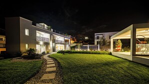 Un bâtiment moderne doté d’une pelouse bien entretenue, d’un chemin en pierre et d’un balcon agrémenté d’une balustrade.