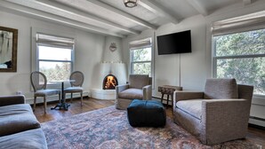 A living room with a fireplace, comfortable seating, and large windows. - Tesuque Outpost |3 Casitas |Best views in Santa Fe (Santa Fe)