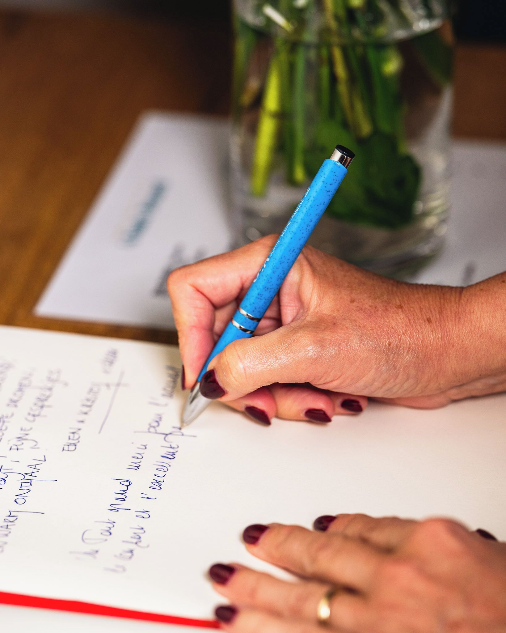 Una mano sosteniendo un bolígrafo azul, escribiendo sobre un papel.