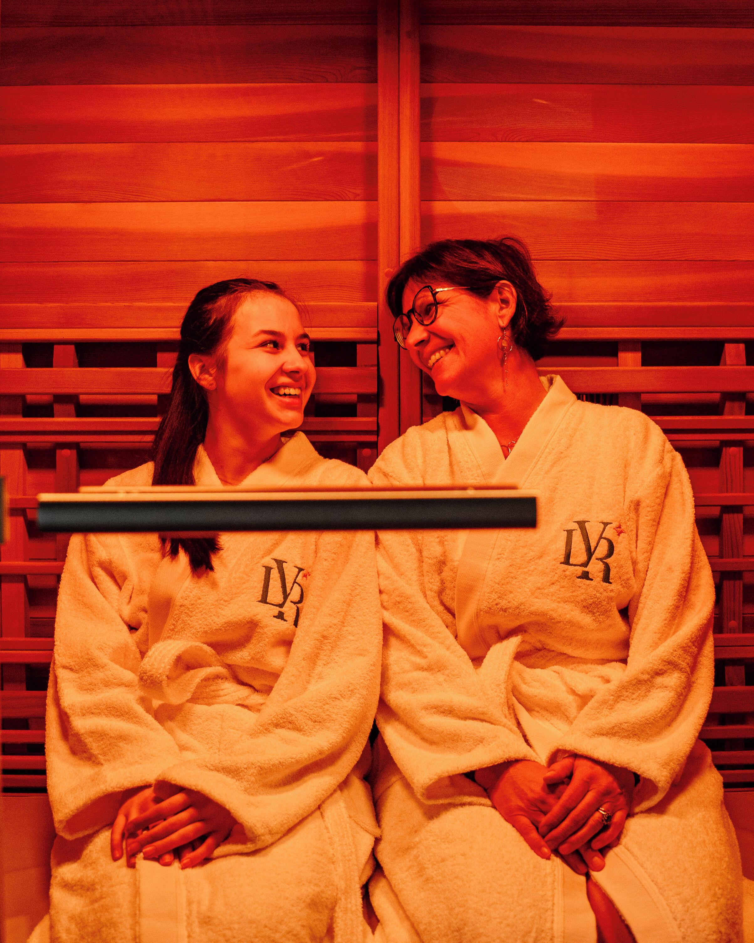 Deux personnes vêtues de robes blanches, sur fond en bois.
