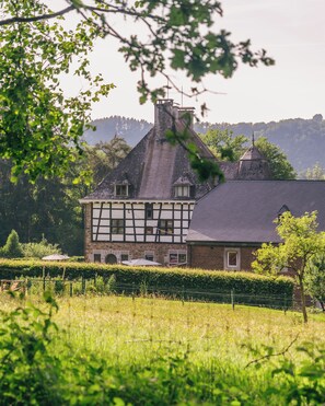 A traditional half-timbered house with a steep roof, surrounded by lush greenery and a fenced field. - Les chambres de la Vaulx-Renard (Stoumont)