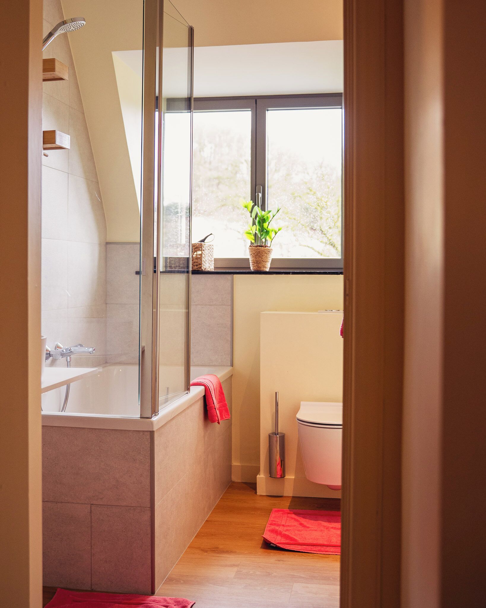 A modern bathroom with a glass-enclosed shower, a toilet, and a window with a view.