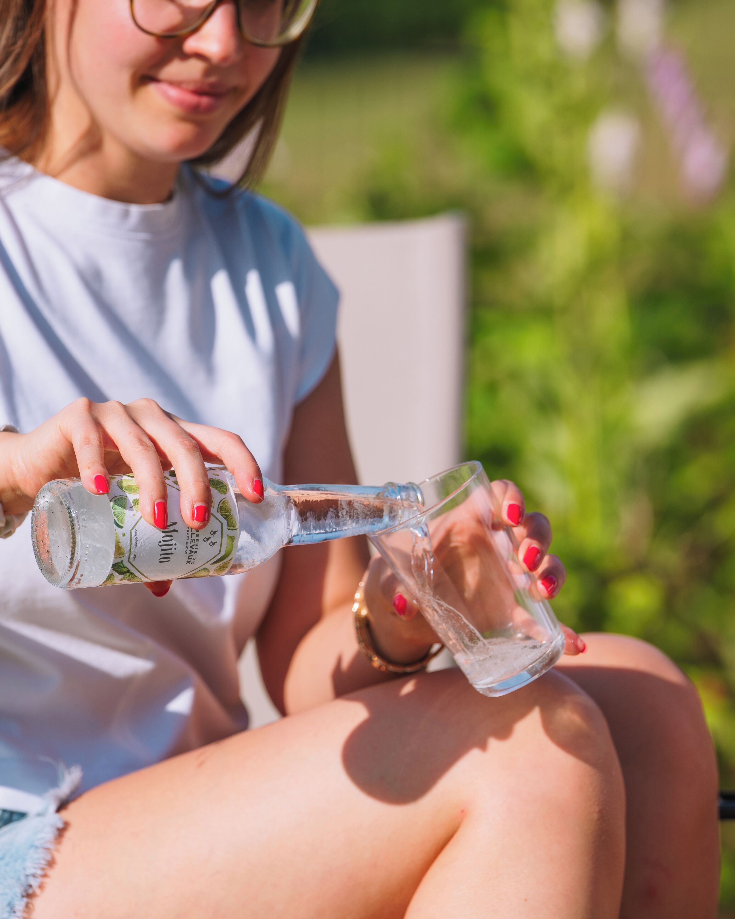 A person pouring a clear liquid from a bottle into a glass.