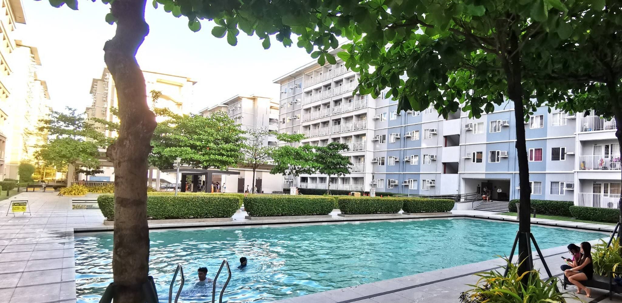 A swimming pool surrounded by a landscaped area with a building in the background.