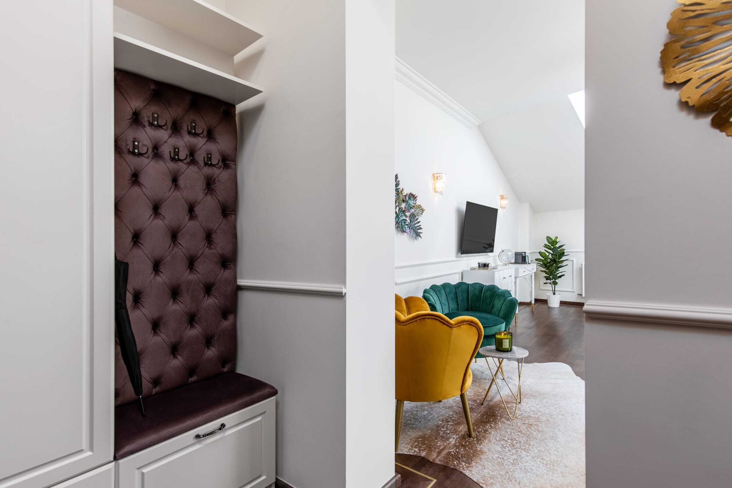 Un interior moderno con un cabecero capitonado, un sofá verde, un sillón amarillo y un televisor de pantalla plana en una sala de estar.