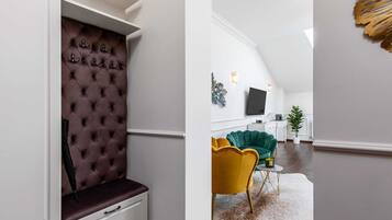 Un interior moderno con un cabecero capitonado, un sofá verde, un sillón amarillo y un televisor de pantalla plana en una sala de estar.