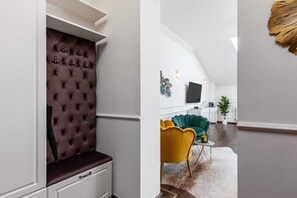 Un intérieur moderne avec une tête de lit capitonnée, un canapé vert, un fauteuil jaune et un téléviseur à écran plat dans l’espace de vie.