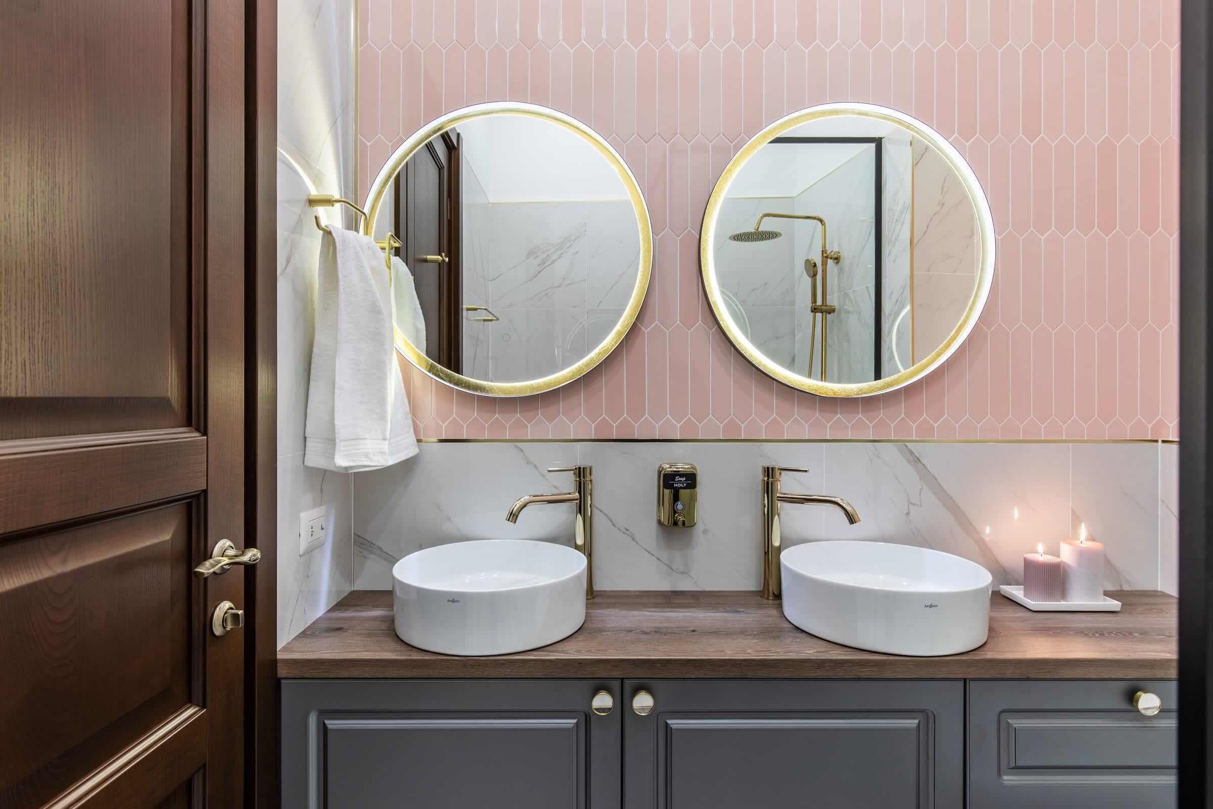 Un baño con dos lavamanos, un espejo y un perchero para toallas.