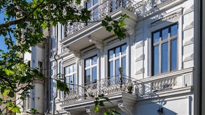A historic building with ornate balconies, large windows, and a cobblestone street.