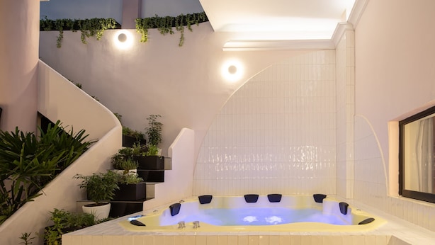 A modern spa area with a hot tub, indoor plants, and a staircase. - HOLT Hotel De Mi Independencia Double Queen Room (Oaxaca de Juárez)