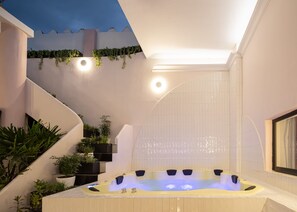 Un área de spa moderna con un jacuzzi, plantas de interior y una escalera.