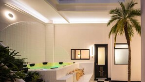 A modern interior with a checkered floor, a palm tree, and a spa area with a bathtub and seating. - HOLT Hotel De Mi Independencia Double Queen Room (Oaxaca de Juárez)