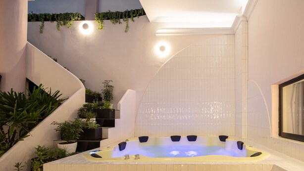 A modern spa area with a hot tub, indoor plants, and a staircase.