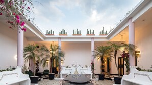 A spacious courtyard with a central round table, white benches, and potted plants.