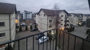 A residential area with multi-story buildings, a paved courtyard, and parked cars. - Rocktop Refuge In Rasnov (Rasnov)