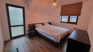 A bedroom with a bed, a nightstand, a dresser, a window with a view, and a ceiling light. - Rocktop Refuge In Rasnov (Rasnov)
