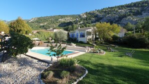 Propiedad residencial con piscina, césped cuidado y montañas al fondo.