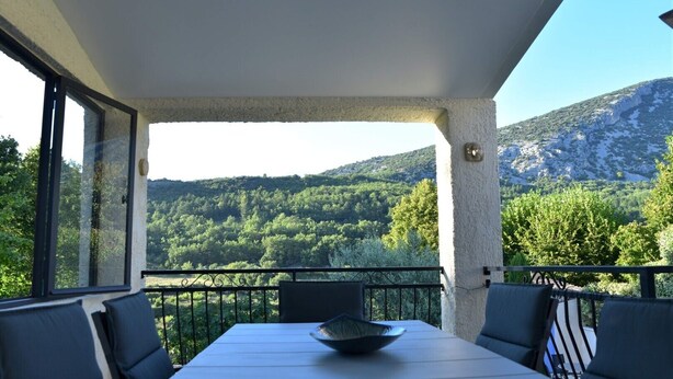 Un balcón con mesa y sillas, con vistas a un paisaje montañoso.