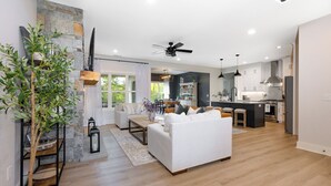 Una sala de estar moderna con un sofá blanco, piso de madera y una planta grande.