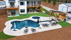 Una casa moderna con un amplio patio trasero que cuenta con una piscina, mobiliario exterior y un área de patio techada.
