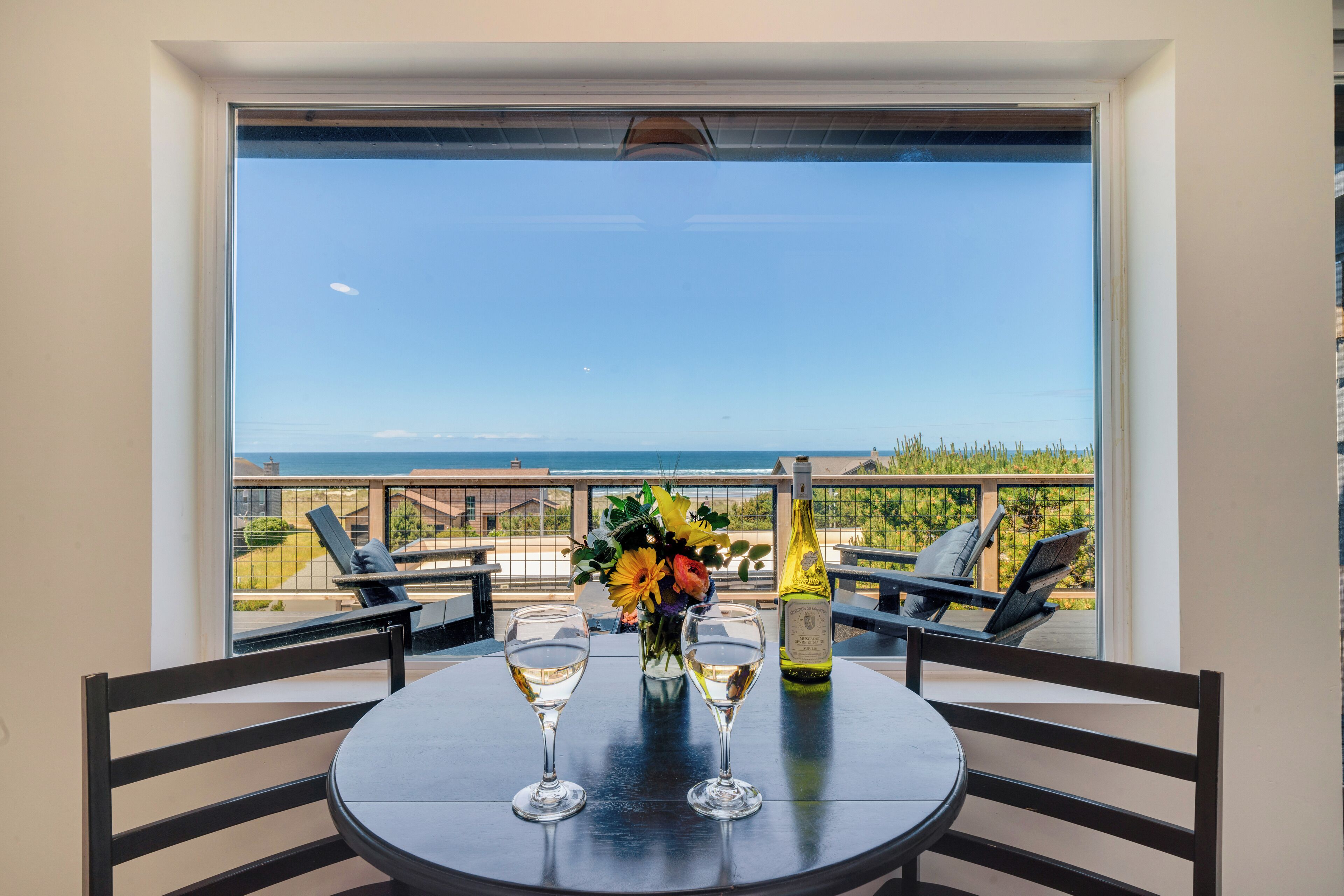 A balcony with a table, two wine glasses, and a bottle of wine.