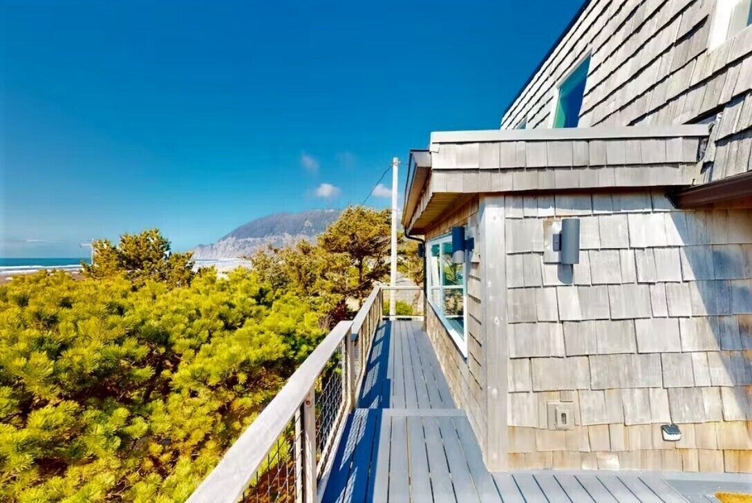 Una terraza de madera con vista al océano y las montañas.