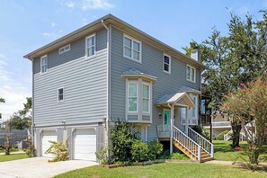 A two-story residential building with a front porch, a staircase leading to the entrance, and a garage. - Sweet Sunset | Rooftop Deck, Short Walk to Beach! (Tybee Island)
