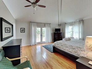 A bedroom with a bed, a desk, a chair, a dresser, a television, and a ceiling fan. - Sweet Sunset | Rooftop Deck, Short Walk to Beach! (Tybee Island)