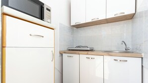 A kitchen with white cabinets, a wooden countertop, a microwave, and a sink.