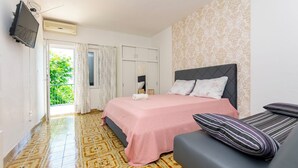A bedroom with a bed, a TV, a wardrobe, and a balcony with curtains.