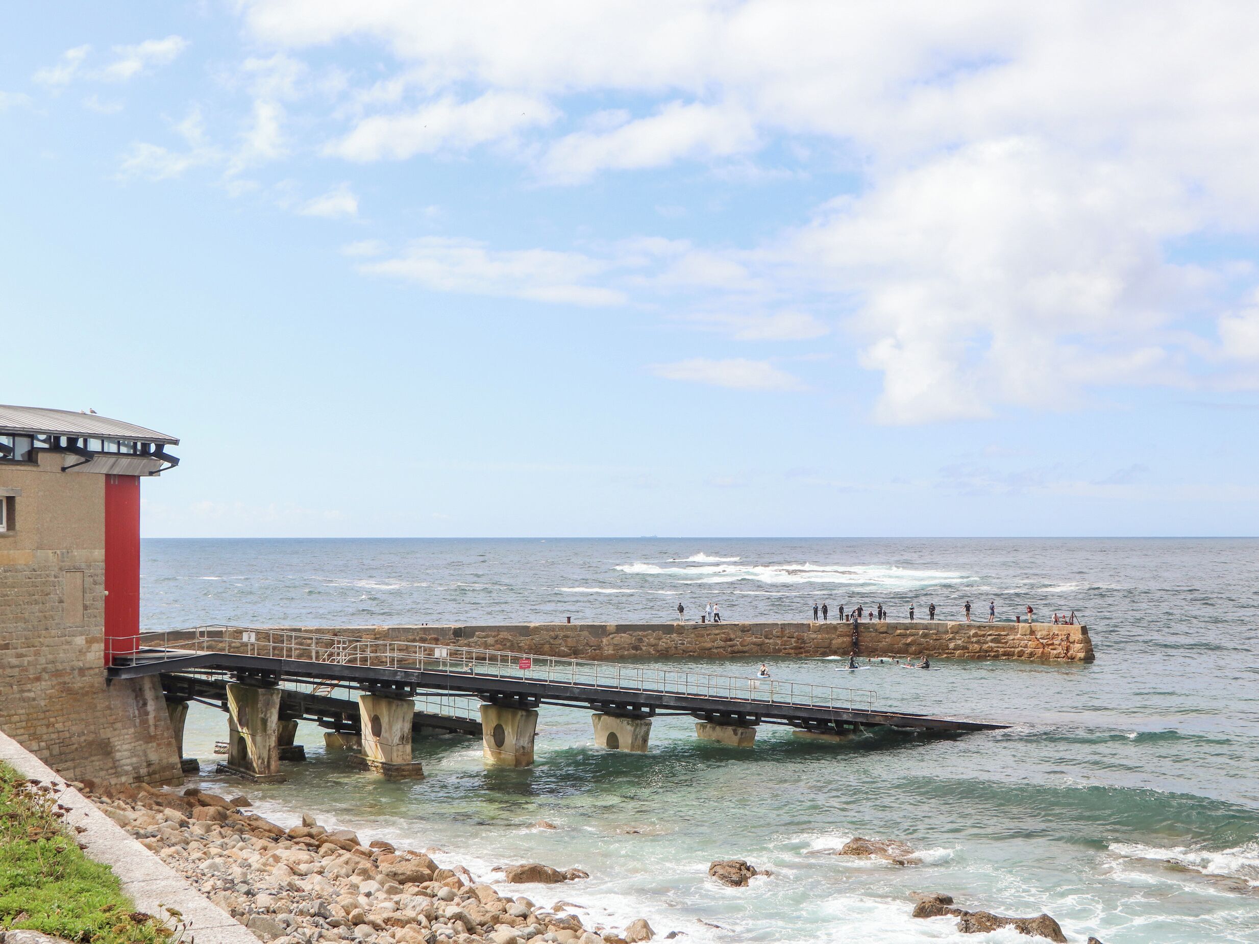 A pier extending into the sea with a building on the left.