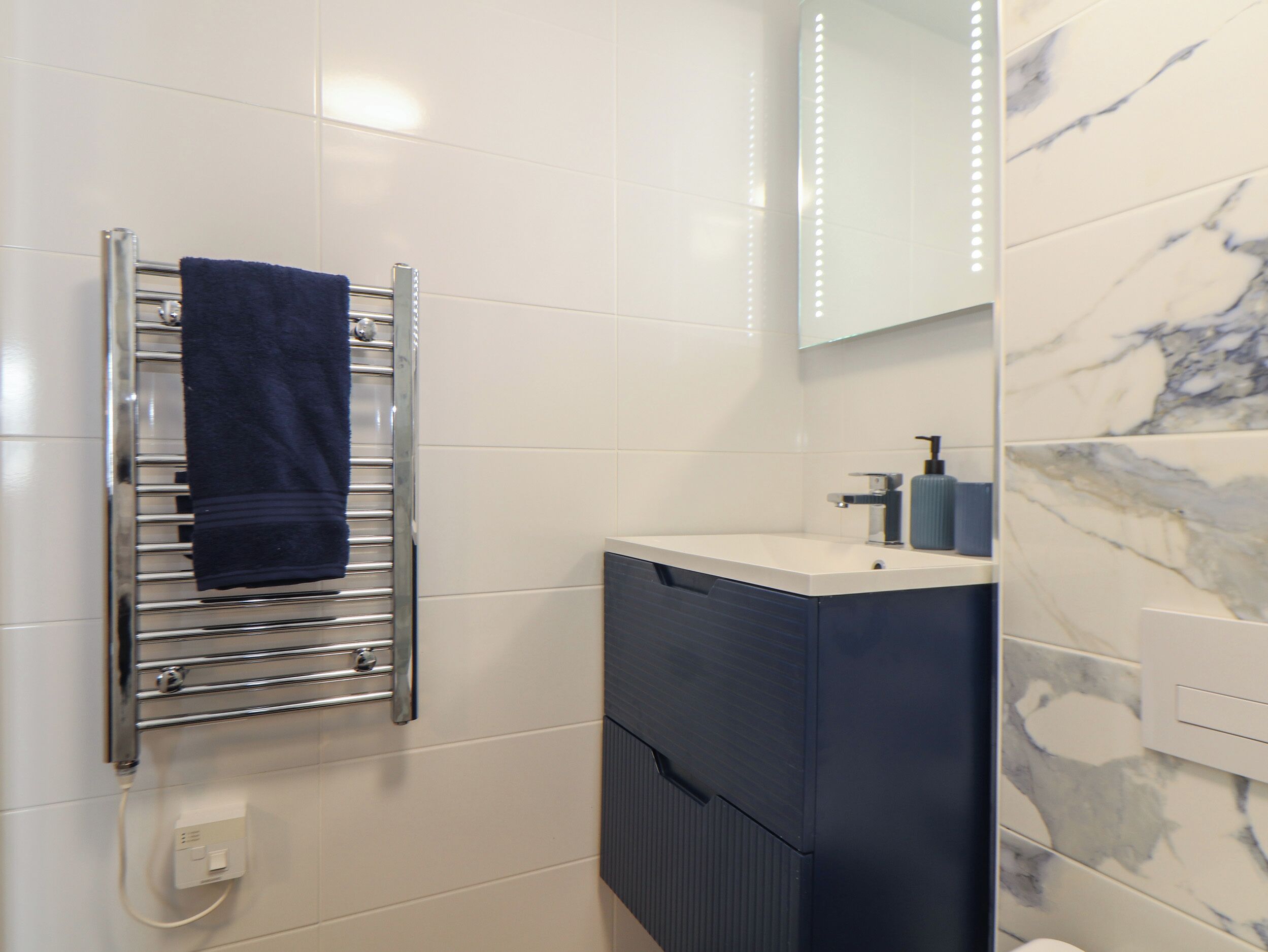 A bathroom with a towel rack, a sink, and a mirror.