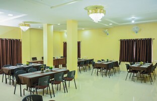 Uma sala de conferência com várias mesas e cadeiras, paredes amarelas e ventiladores de teto.