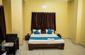 A neatly arranged bedroom with a bed, two bedside tables, a chair, and a curtain. - THE SHRINE HOTEL (Khandwa)