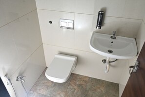 A bathroom with a toilet, sink, and shower. - THE SHRINE HOTEL (Khandwa)