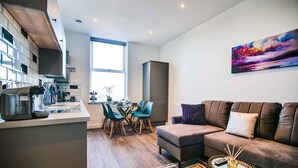 A modern kitchen with a dining area, a sofa, and a painting on the wall. - Apartment 3 - The Crescent (York)