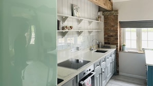 A kitchen with white cabinets, a stainless steel sink, and a vintage-style refrigerator. - The Hayloft (Crewe)