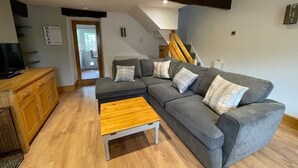 A modern living room with a grey sectional sofa, wooden coffee table, and a staircase leading to an upper level.