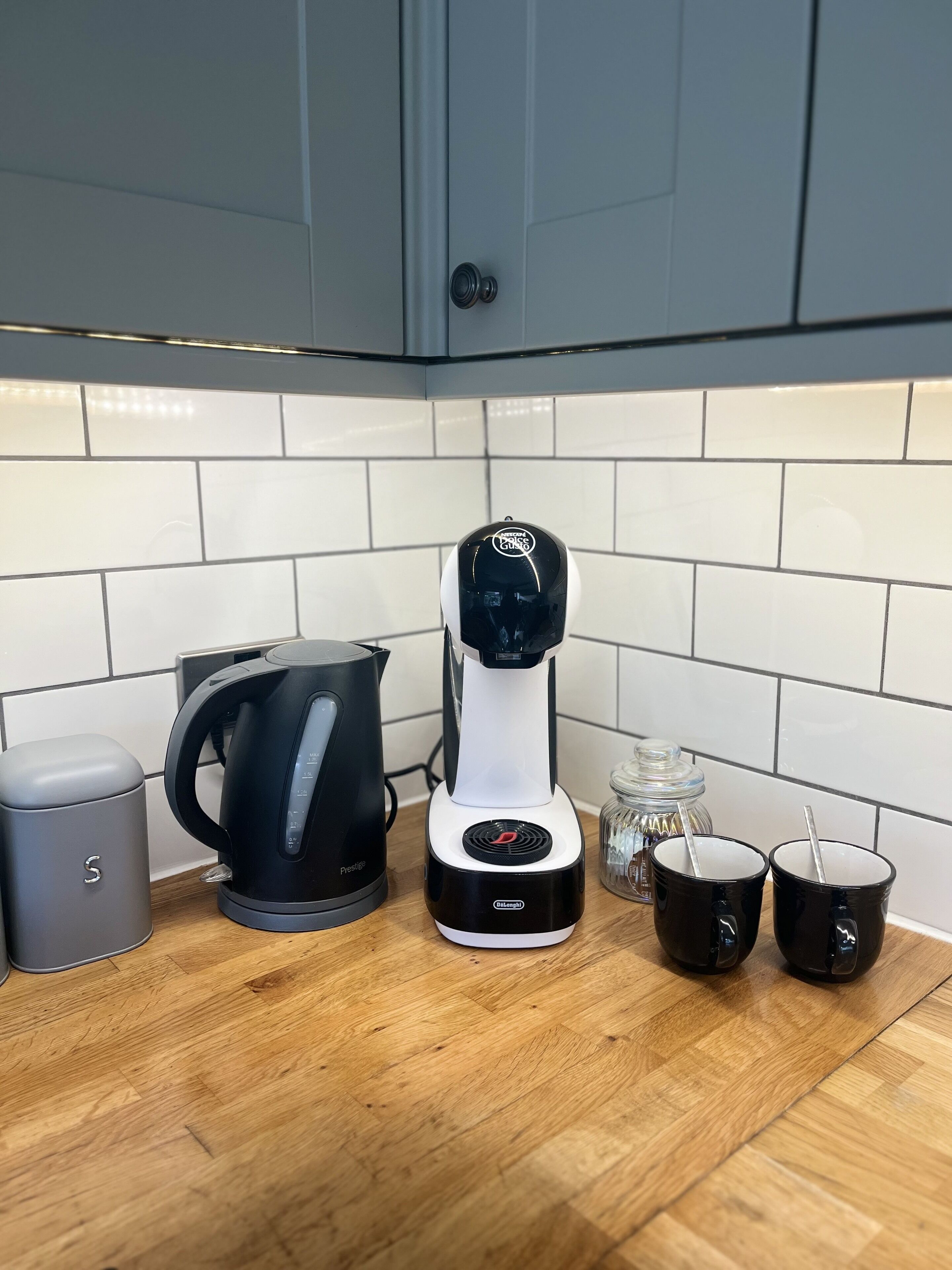 Eine Küche mit Kaffeemaschine, Wasserkocher, Mülleimer und zwei Tassen auf der Arbeitsplatte.