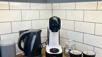 Eine Küche mit Kaffeemaschine, Wasserkocher, Mülleimer und zwei Tassen auf der Arbeitsplatte.