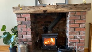 A brick fireplace with a wood-burning stove, a metal pot, and a black bucket on a stone hearth.