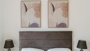 A bedroom with a grey headboard, two white pillows, and two bedside lamps. - Apartment 9 (York)