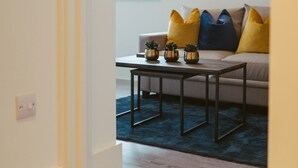 A modern living room with a sofa, coffee table, and decorative pots. - Apartment 9 (York)